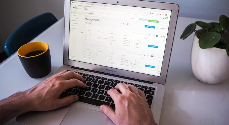 person using macbook air on white table