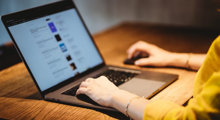 person using macbook pro on brown wooden table