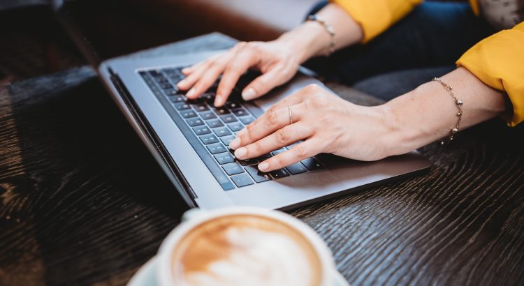 person using macbook pro on brown wooden table